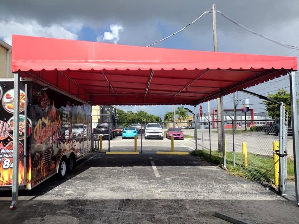 Red commercial awning covering a food truck service bay
