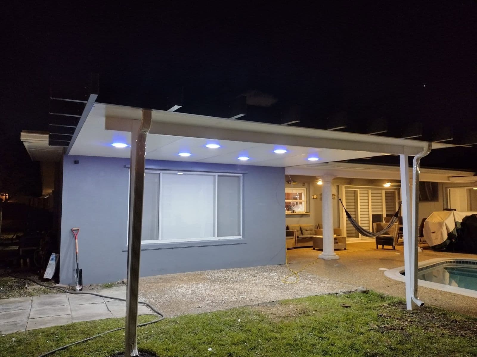 White patio cover with LED lighting over a poolside patio